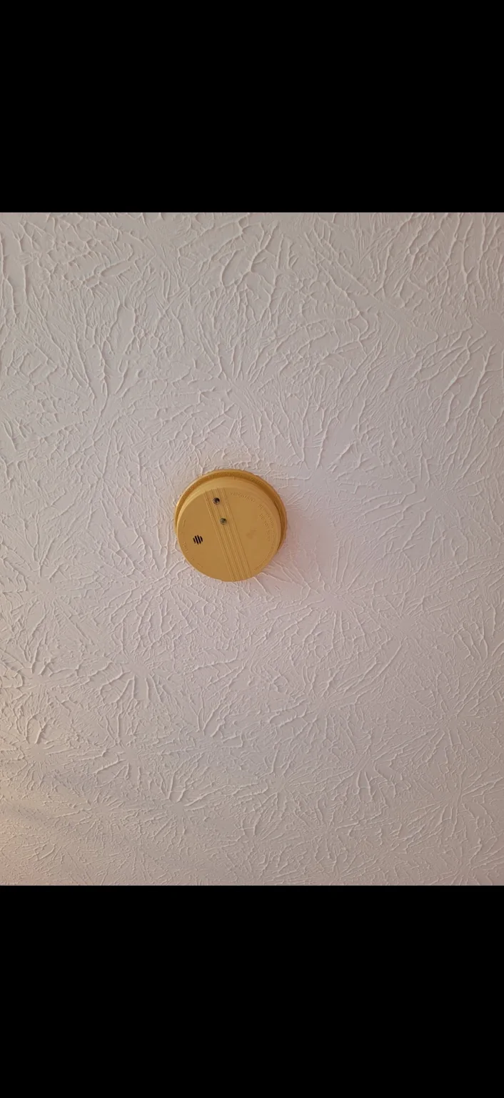 Older smoke alarm. An older, discolored alarm photographed as existing equipment.