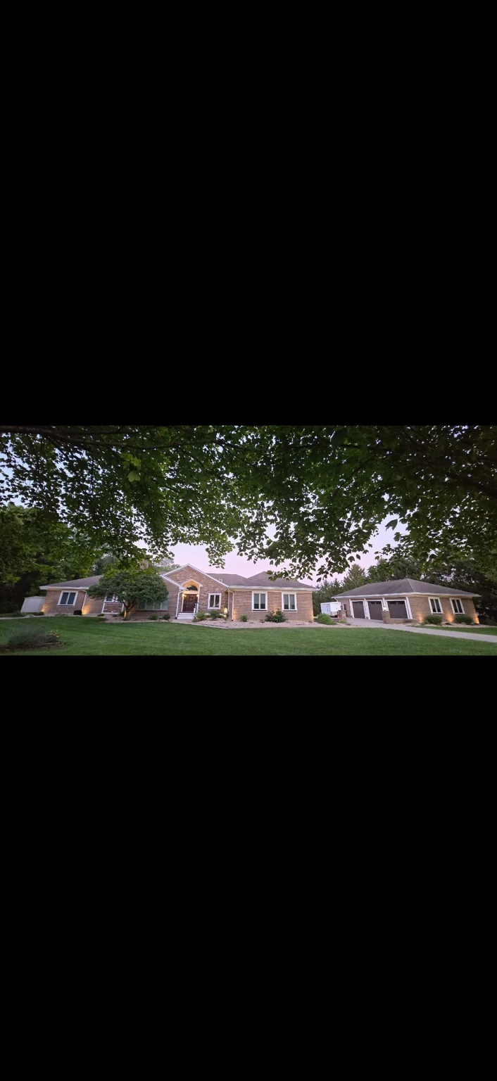 Architectural lighting at dusk. A wide view of accent lighting across a brick home and garage.